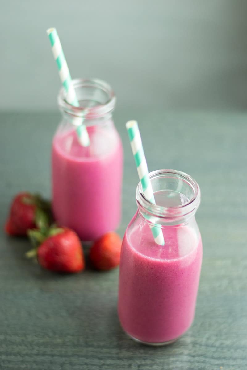 dragonfruit smoothie in two bottles with striped straws