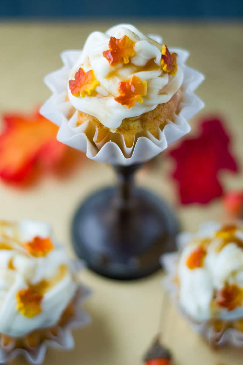 Thanksgiving Carrot Cupcakes - Close up of one Thanksgiving themed carrot cupcake with white frosting and fall candy leaves