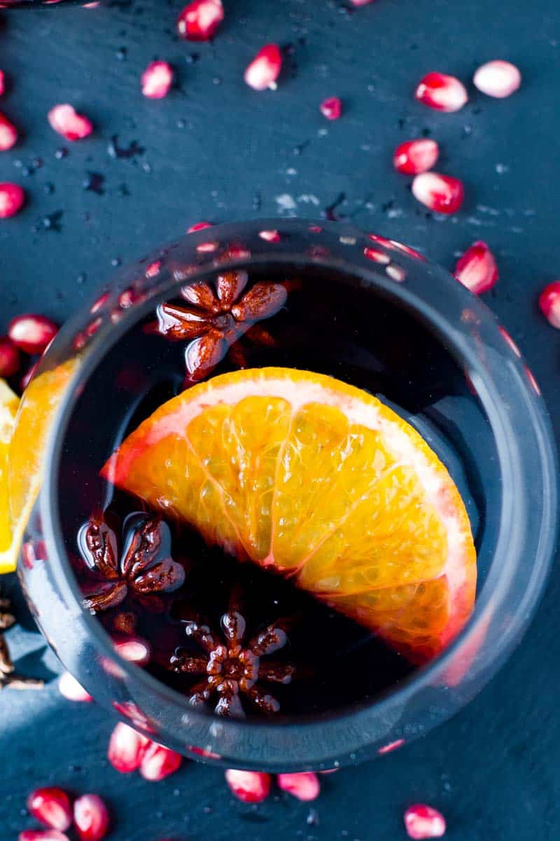 Slow Cooker Spiced Mulled Wine with Pomegranates and Oranges. Floating star anise and cinnamon.