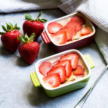 Two ramkeins filled with Keto creme brulee. Three large strawberries to the side.