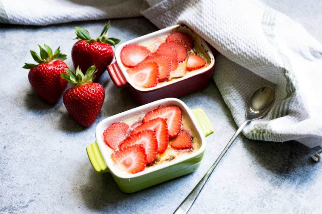 two sideways ramekins, with long spoon and raw strawberries